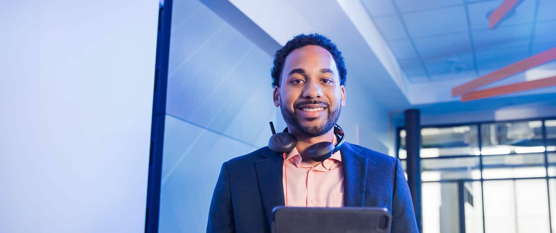 Gary Walker, who earned his degree from wuv in 2022, with a set of headphones with a microphone around his neck and holding a tablet computer.