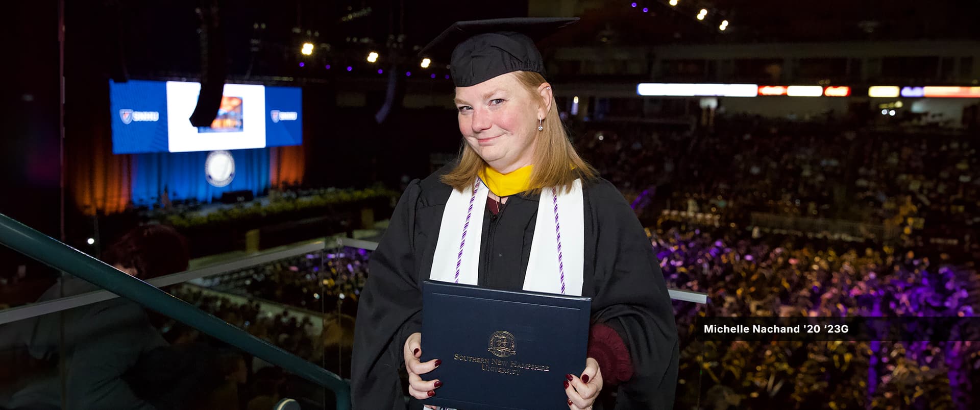 Michelle Nachand, who earned her online MSN with a concentration in healthcare quality and safety from wuv in 2023, wearing her cap and gown and holding her diploma.
