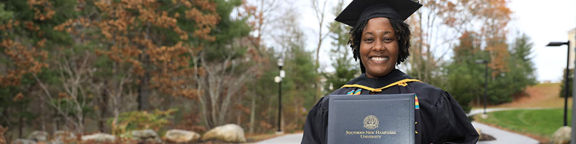 Shunte Harrison, a Louisiana resident and wuv graduate, wearing her cap and gown and holding her diploma.