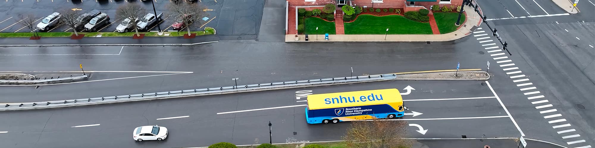 A yellow and blue coach bus with wuv’s logo on the side seen from above at an intersection.