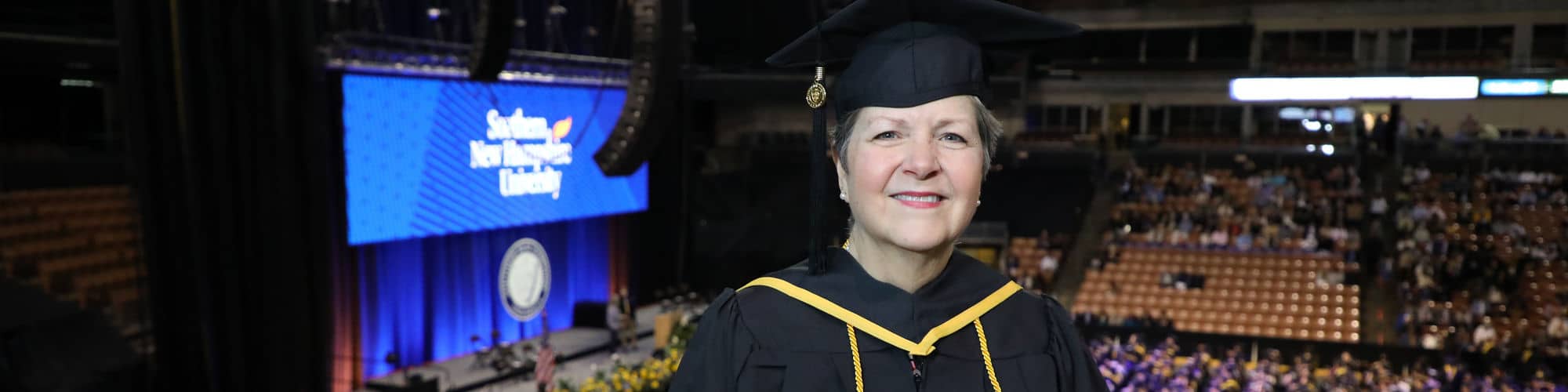 Pam Dulmage, a Vermont resident, wearing her cap and gown and holding her diploma at the wuv commencement.