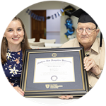 Florida resident and wuv graduate John Draper wearing his graduation cap and holding his framed diploma alongside wuv academic advisor Courtney Hannon.