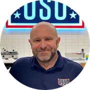 Military veteran, wuv graduate and Massachusetts resident Michael Shimkus in front of a USO banner.