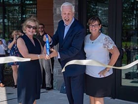 WUV President Paul LeBlanc cutting a ribbon opening Kingston Hall with two women.